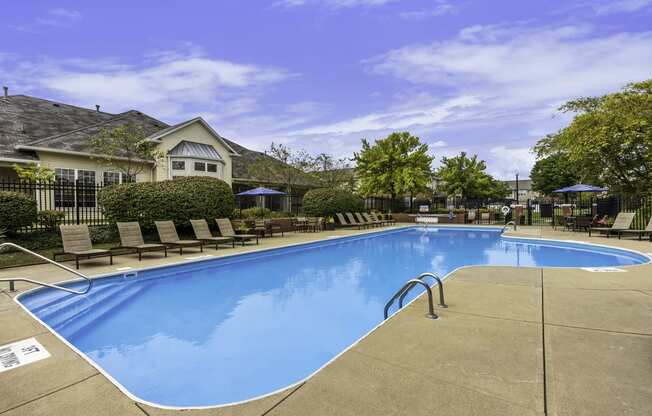 a swimming pool with chairs and a house in the background