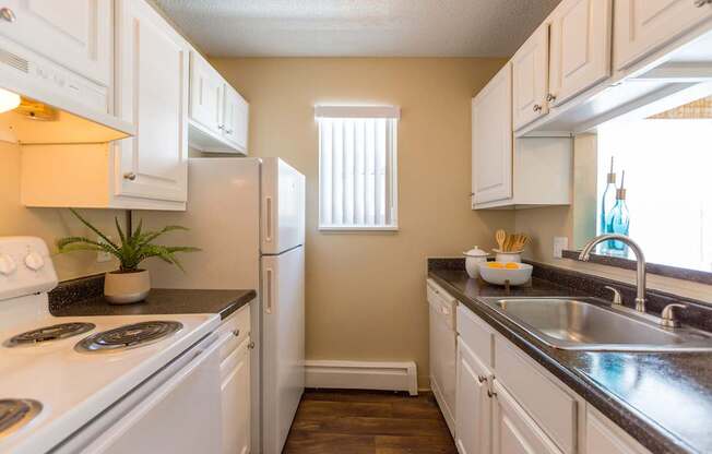 A kitchen with white cabinets and a black countertop.