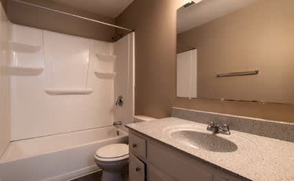 A bathroom with a toilet, sink, and mirror.