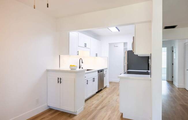 A kitchen with white cabinets and a wooden floor.