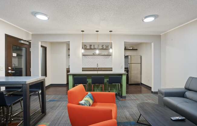 a living room with orange couches and a kitchen with a green bar