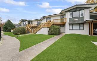 the front of a house with a yard and a staircase