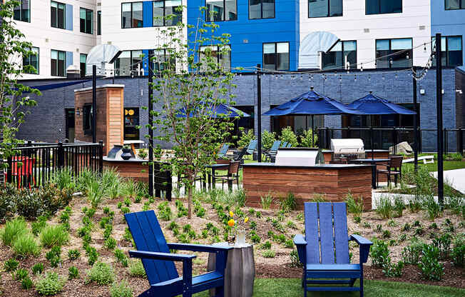 a yard with two blue chairs and a table and an apartment building in the background at Dey & Bergen, New Jersey