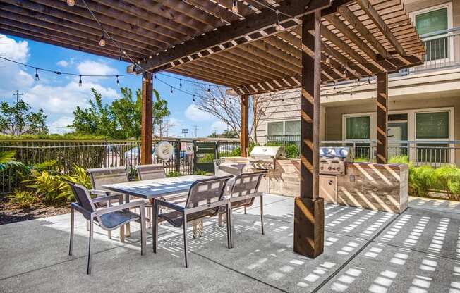 a patio with a table and chairs and a grill