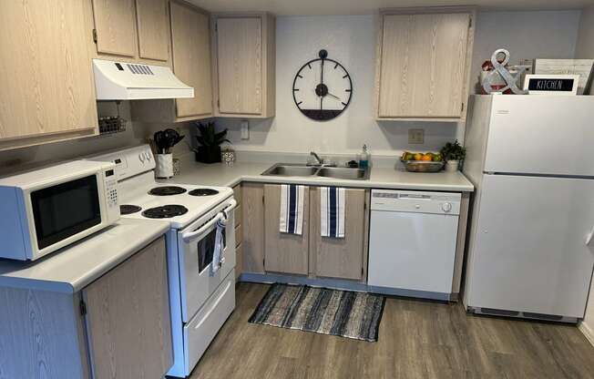 a kitchen with white appliances and a clock on the wall