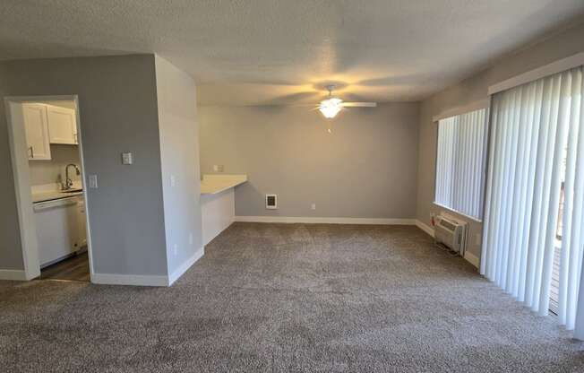 an empty living room with large windows and a ceiling fan