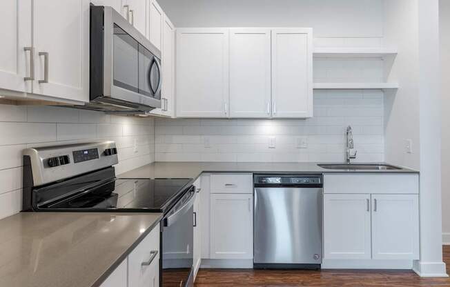 A modern kitchen with white cabinets and stainless steel appliances.