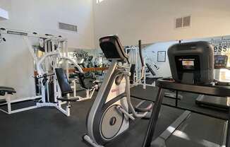 A gym with a treadmill, elliptical trainer and other exercise equipment.