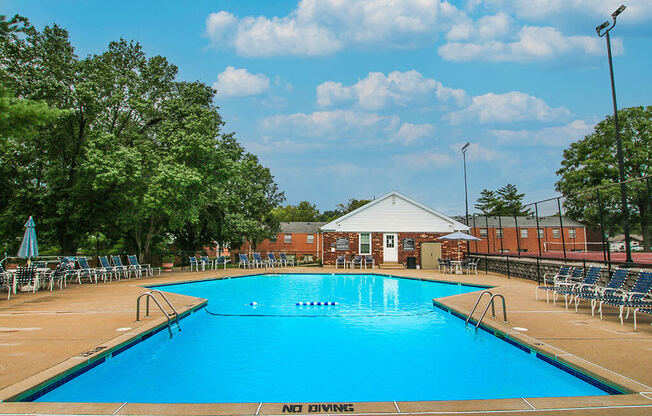 a swimming pool with chairs around it and a building in the background