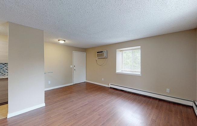 Bright and inviting living space with hardwood floors, large window, and modern kitchen accents.