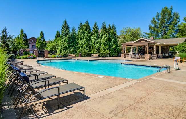 A large swimming pool surrounded by lounge chairs and trees.