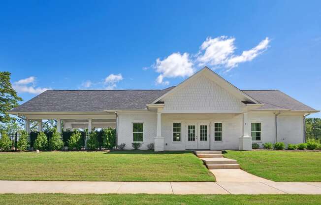 a white house with a green lawn and a blue sky