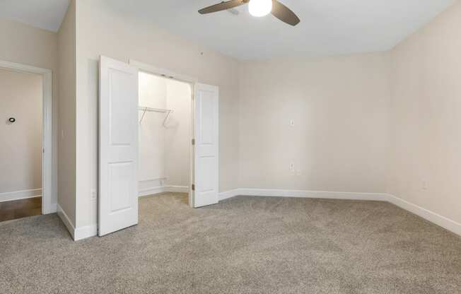 an empty living room with a closet and a ceiling fan