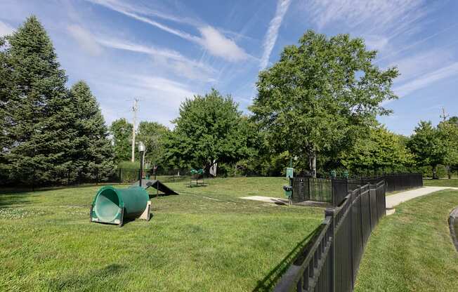 a park with green grass and trees and a black fence