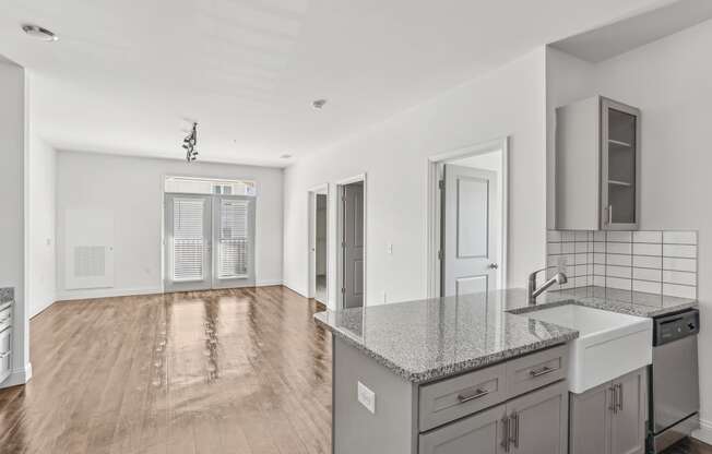 an empty living room with a kitchen with a sink and a counter top