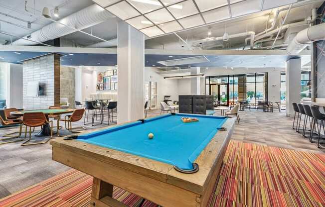 a pool table in a lobby with tables and chairs at Link Apartments Innovation Quarter, Winston Salem, NC