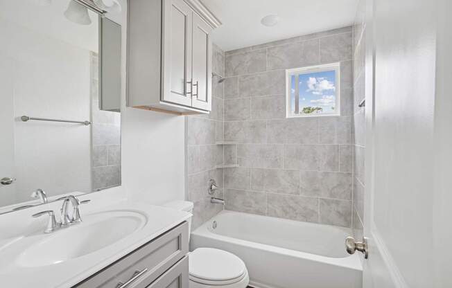 A bathroom with a white tub, sink, and toilet.