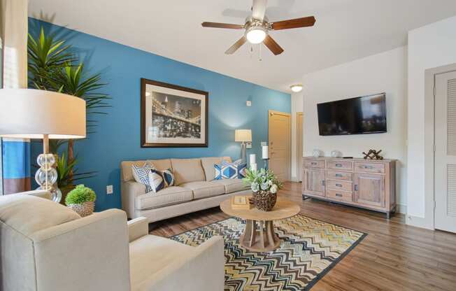 a living room with a blue accent wall and a ceiling fan at Alvista Round Rock, Round Rock, TX