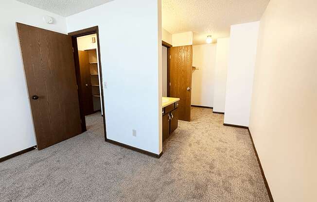 A carpeted hallway with a door on the left and a bench on the right.