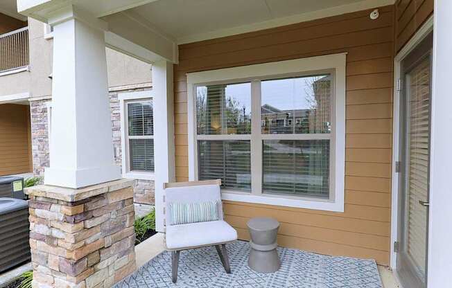 A patio with a white chair and a stone pillar.