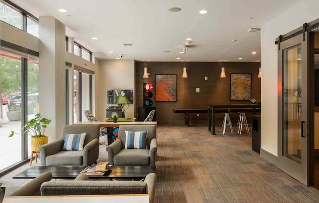 A modern waiting room with grey couches and a wooden floor at Regatta Sloans Lake Apartments, Denver 80204