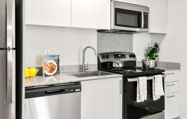 A modern kitchen with a black stove top oven and white cabinets.