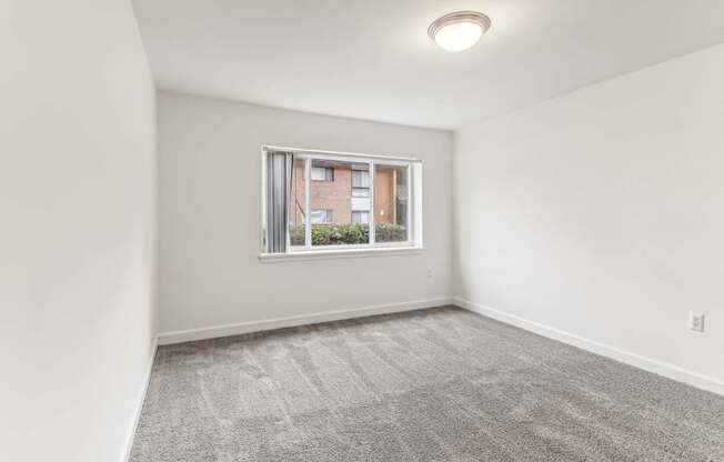 an empty living room with a window and white walls