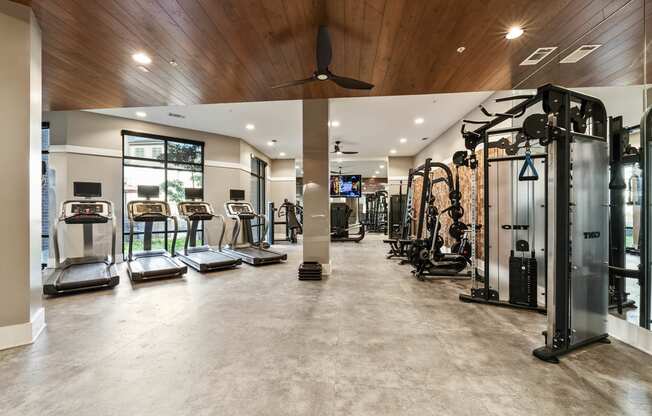 a gym with cardio equipment and a ceiling fan