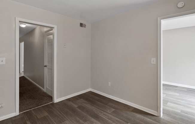 an empty room with a hallway and a door to a bedroom