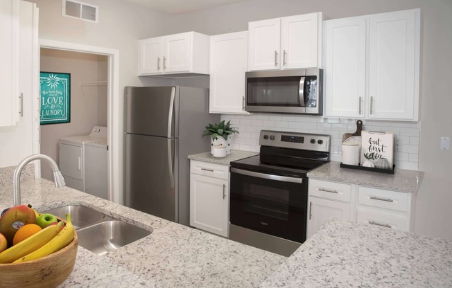 Upgraded kitchen with white cabinetry, stainless steel appliances, and granite countertops.