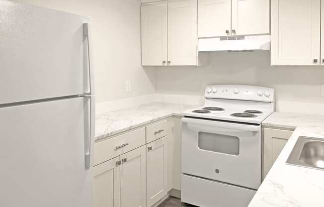 Updated kitchen with white top and bottom cabinets, full-size fridge, oven, stovetop, rangehood, sink, and dishwasher. at Talavera, Boise, 83705