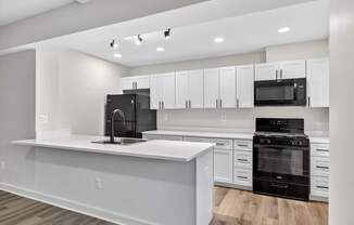 A modern kitchen with white cabinets and black appliances.