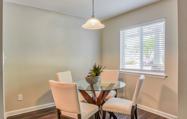 a dining room with a glass table and four chairs