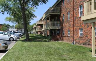 a grassy area with a tree in front of a brick building