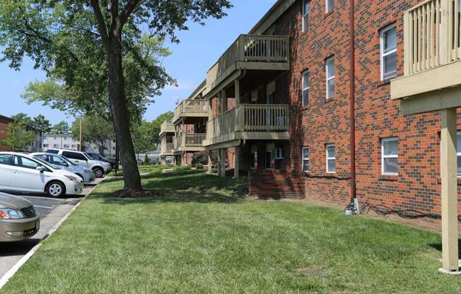 a grassy area with a tree in front of a brick building