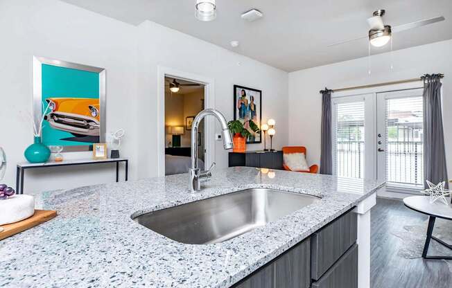 A modern kitchen with a granite countertop and a stainless steel sink.