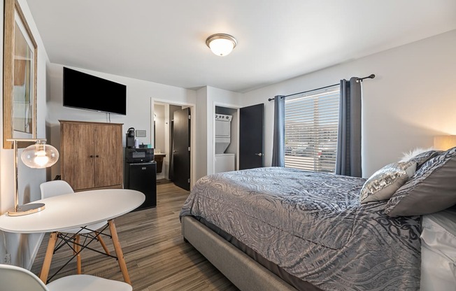 a bedroom with a bed and a small white table and chairs