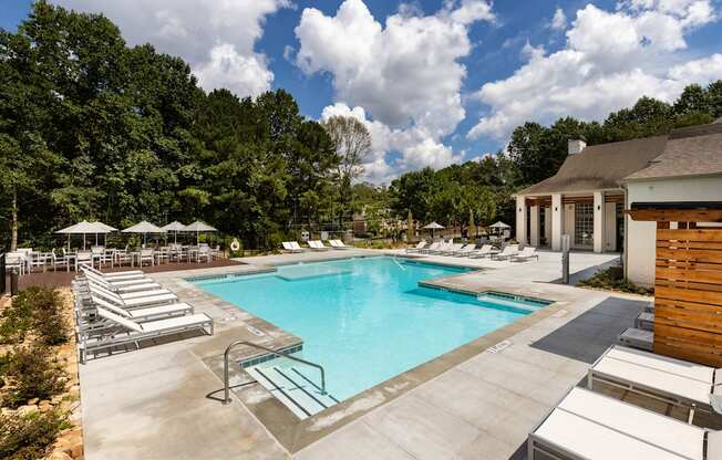 A large swimming pool surrounded by sun loungers and umbrellas.