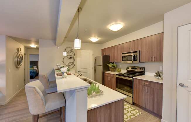 Kitchen with Countertop, Elevated Cushioned Chairs, Wood Inspired Floor, Oven, Wood Cabinets, Ceiling Lights