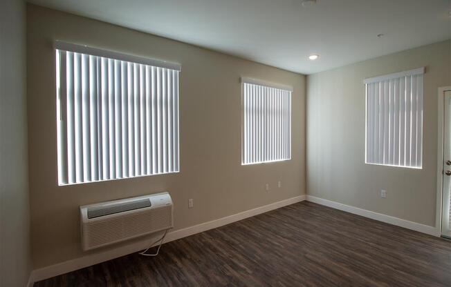 an empty room with three windows and a radiator at Loma Villas Apartments, San Bernardino, CA