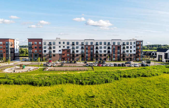 A large grassy field in front of a row of apartment buildings.