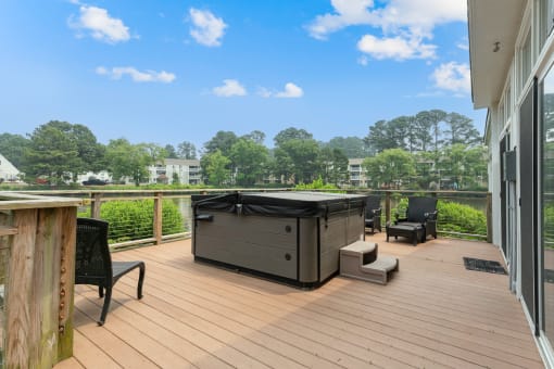 a hot tub on a deck with chairs and trees in the background at Linkhorn Bay Apartments, Virginia, 23451