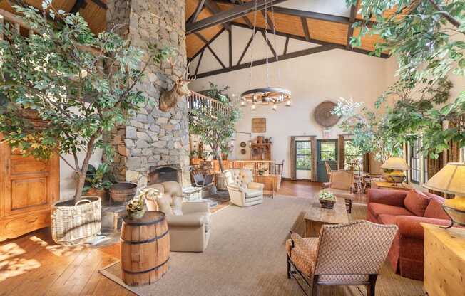 A clubhouse living room with a stone fireplace and wooden furniture.