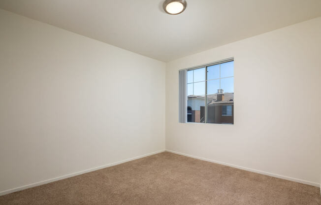 an empty room with a window and carpet