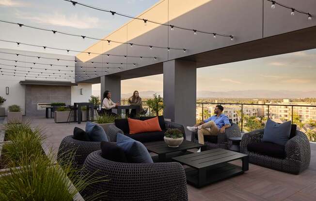 A group of people are sitting on a patio with a view of the city.