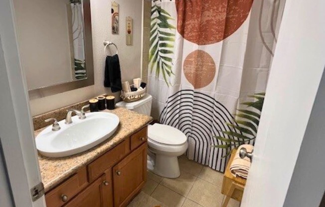 A bathroom with a sink, toilet, and shower curtain.