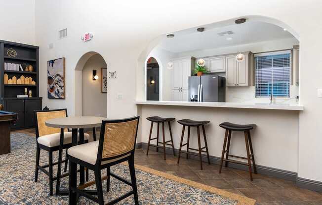 A kitchen with a bar area featuring a black fridge and bar stools.