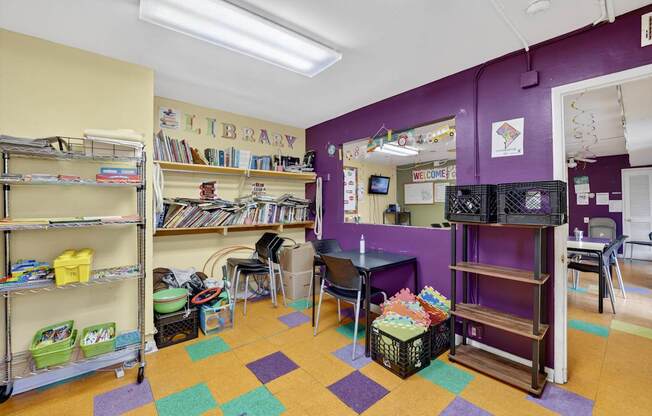 A library with purple walls and a variety of books on shelves.