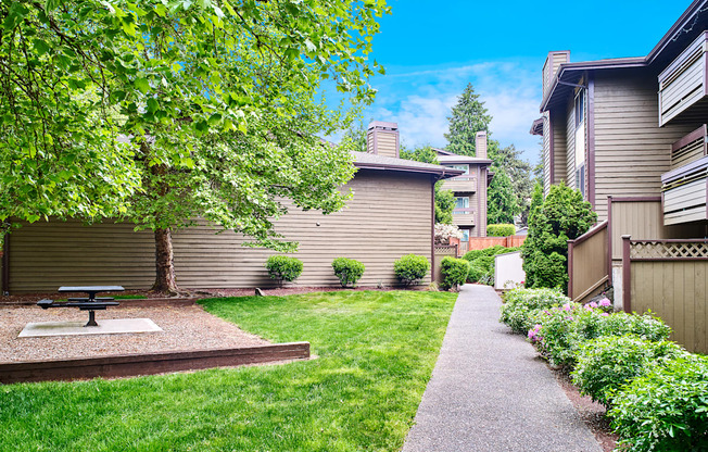 A backyard with a picnic table and a concrete path at apartments in Renton, WA.