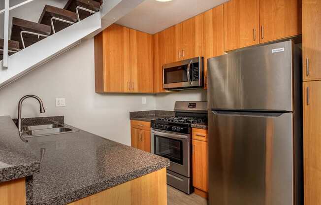 A kitchen with a stainless steel refrigerator and wooden cabinets.